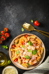traditional italian kitchen. Italian pasta alla arrabiata with basil and parmesan on dark table. Top view with copy space.