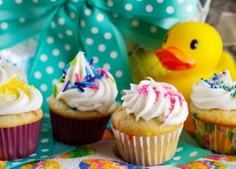 A close up view of assorted mini cupcakes with Easter basket in background.