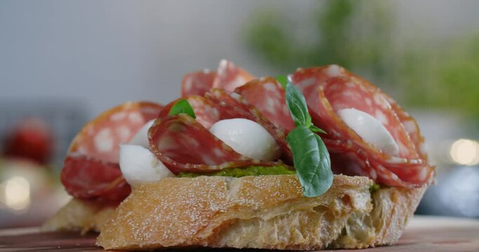 Bruschette with salami and mozarella is sprinkled by the raw green herbs in slow motion, 4k 60p Prores