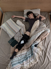 Woman with ACL surgery sleeping in bed at home.
