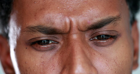 Naklejka premium Worried african man closeup eyes squinting, concerned preoccupied black guy macro close-up