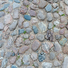fragment of a stone path made of stones of different sizes and colors on the territory of the Pskov Kremlin, Russia