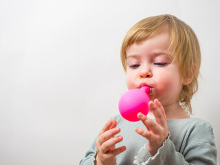 little girl trying to inflate a balloon with her lips
