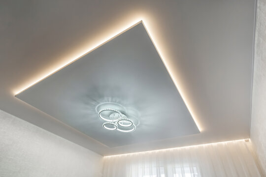 suspended ceiling with halogen spots lamps and drywall construction in empty room in apartment or house. Stretch ceiling white and complex shape.