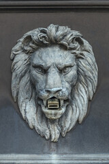 concrete sculpture of the head of a formidable lion on the facade of the fountain