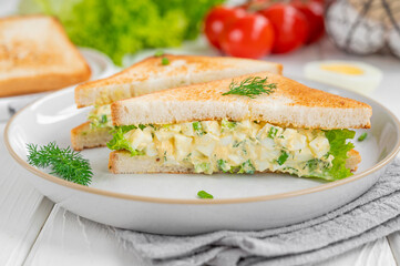 Egg salad sandwich with toasted bread and lettuce on a white wooden background. Selective focus