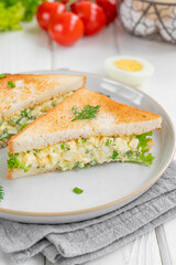 Egg salad sandwich with toasted bread and lettuce on a white wooden background. Selective focus
