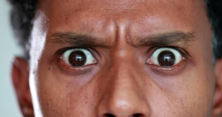Surprised African descent close-up eyes reaction, looking to camera. Back person eye SHOCK - obrazy, fototapety, plakaty