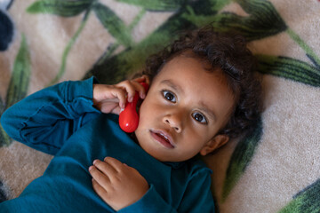 Latin American boy (2) holds a toy headset to his ear while playing on the phone. Children's technology concept