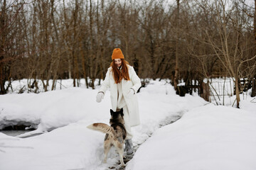 Happy young woman outdoors in a field in winter walking with a dog fresh air