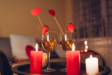 Valentines day celebration at home with champagne wine glasses with strawberries on top surrounded...
