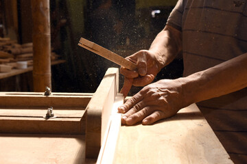 Carpenter's hands cutting the wood to make a piece of furniture in his carpentry workshop.