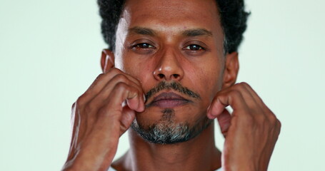 Person massaging his own face close-up. African man touching face relaxing and resting