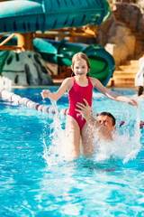 dad throws up his daughter, they have fun and play together in the pool. 