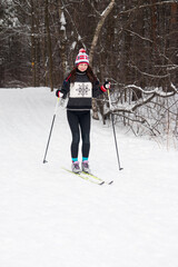 young woman skiing in the park. White winter forest and skier