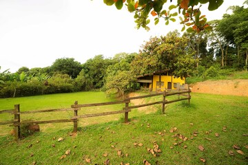 Casa amarela da fazenda terreno gramado com uma cerca de madeira. Casa da Fazenda imóvel  antigo....