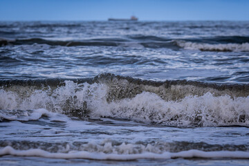 View of the Baltic Sea from the beach with the ship blurred in the background
