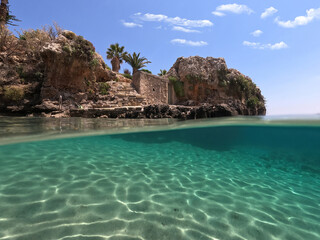 Fototapeta premium Underwater split photo of small bay and pituresque village of Avlemonas with emerald crystal clear sea in island of Kythira, Ionian, Greece
