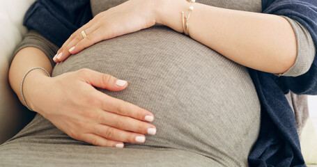 The bond of creation. Shot of an unrecognizable pregnant woman holding her belly at home.
