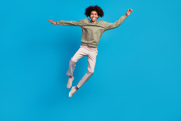Fototapeta premium Full size photo of young cheerful guy have fun jump up rejoice travel isolated over blue color background