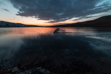 Beautiful long exposure landscape. Small lake and mountains after sunset with dramatic clouds.