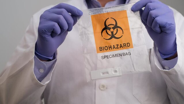 Doctor in gloves  holding Biohazard Specimen Bag with Positive PCR Antigen Test, Copy space pandemic concept