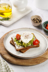 Fototapeta na wymiar Trendy lifestyle sandwich: protein bread slice with cream cheese, mashed avocado, cherry tomatoes and poached egg on white scandi plate, light setting