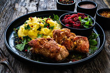 Wrapped pork with potato puree and red beets on wooden table
