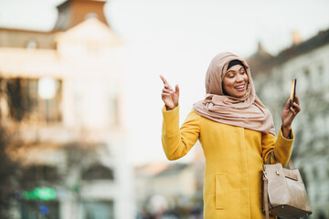 Black Muslim Woman With Hijab Making A Video Call By Smart Phone On The Street
