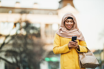 Black Muslim Woman With Hijab Using Smart Phone On The Street