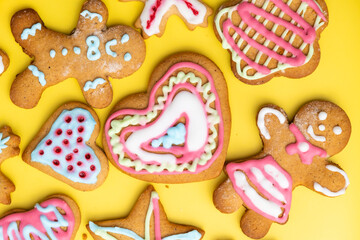 Fototapeta na wymiar Heart shaped sugar cookies and boy and girl gingerbread for St Valentines Day with colorful icing on the yellow background. 