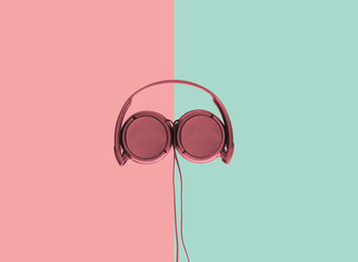 Computer headphones. Red headphones on a green-red pastel background. The concept of listening to...