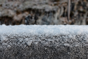 Snow on a concrete fence close-up. Blurred background. Winter in Norway
