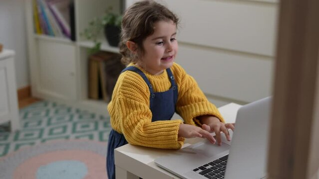 Smiling caucasian girl playing on computer game, happy kid using computer for online class, home education concept