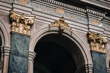 Arch and pilasters with gold Corinthian capitals inside the Jesuit Cathedral in Lviv, Ukraine. Medieval interior design concept. - obrazy, fototapety, plakaty