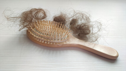 Close-up of a brush with lost hair on it on white wooden table.