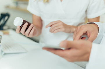 Pharmacist hands holding a bottle of medicine and a tablet