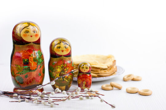 Background with pancakes, wooden dolls matryoshka, sushki and pussy-willow on white for Maslenitsa festival.