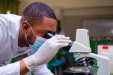 close up of a african doctor looking at the a sample through the mircoscope