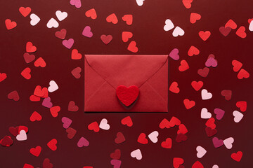 Craft envelope with a blank sheet of paper inside and red heart on the red background. Romantic love letter for the Valentine's day concept. Space for text.