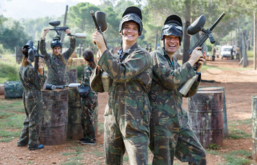 Fototapeta premium Two smiling paintball players in full gear having fun before game outdoors