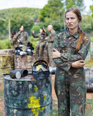 Portrait of upset girl standing with protective helmet with the splash of paint after direct hit in paintball game