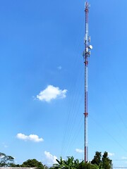 Telecommunication tower with blue sky and white clouds background. Antenna on blue sky. Radio and satellite pole. Communication technology. Telecommunication industry. Mobile or telecom 4g network.