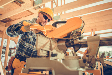 Contractor Worker Trimming Pieces of Wood Beams in a Construction Zone