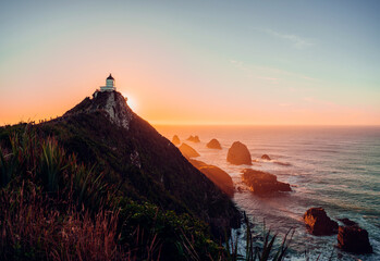 Lighthouse and huge rocks in the ocean at sunrise