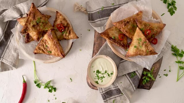 Indian samosas  - fried or baked pastry with savoury filling, popular Indian snacks, served in areca leaf dishes with spices on kitchen countertop.