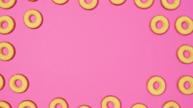 Moving biscuit cookies frame for text on vibrant pink theme. Stop motion flat lay