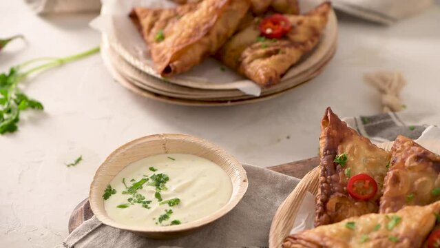Indian samosas  - fried or baked pastry with savoury filling, popular Indian snacks, served in areca leaf dishes with spices on kitchen countertop.
