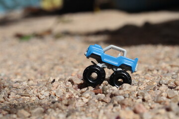 A blue toy car on coarse sand