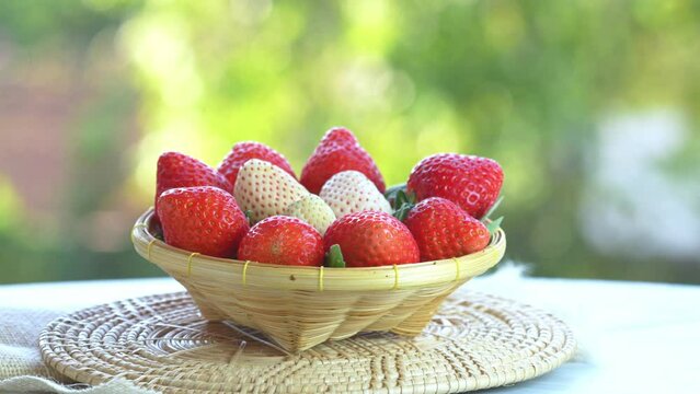 Red and white strawberries in a wooden basket on blur background, Red Strawberry and Pine berry or Hula strawberry in Bamboo basket.
